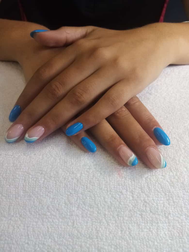 A close up of a woman 's hands with blue nails on a white towel.