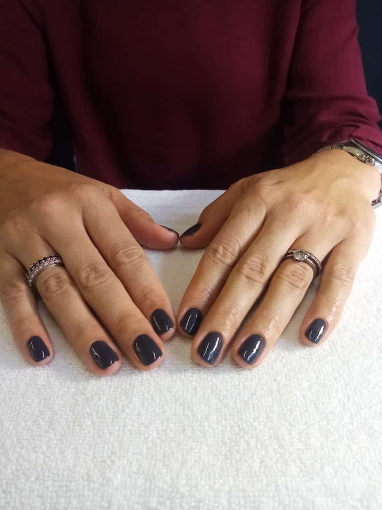 A close up of a woman 's hands with black nails and rings