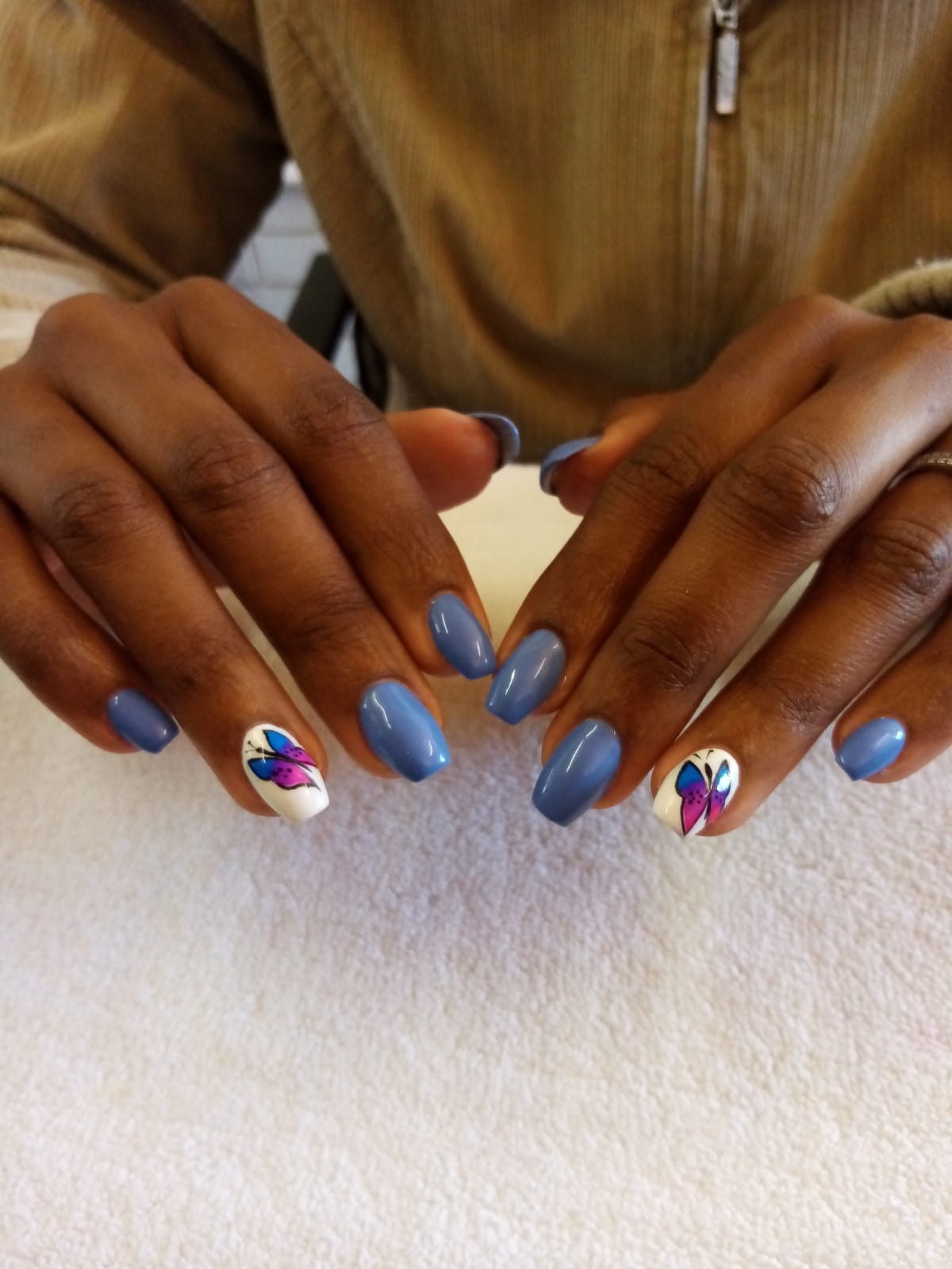 A woman 's nails are painted blue and white with a butterfly design