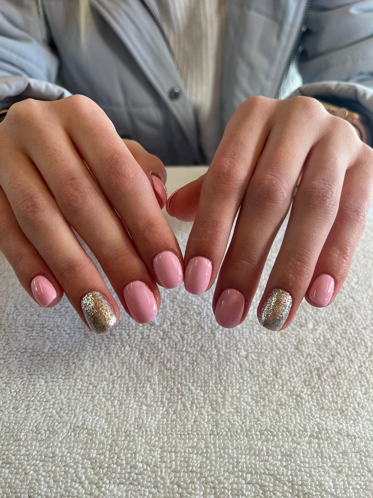 A close up of a woman 's hands with pink and gold nails.