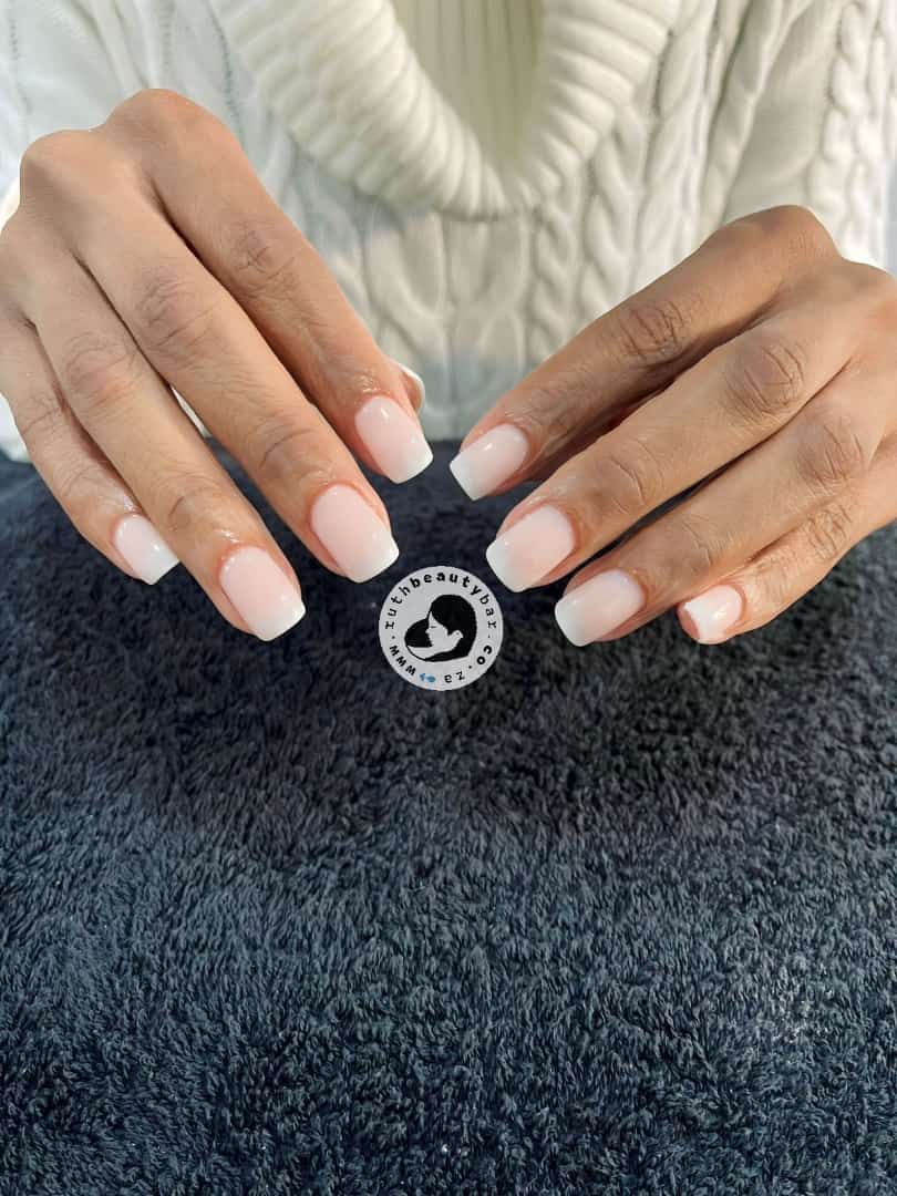 A woman 's hands with white nails are holding a black item.