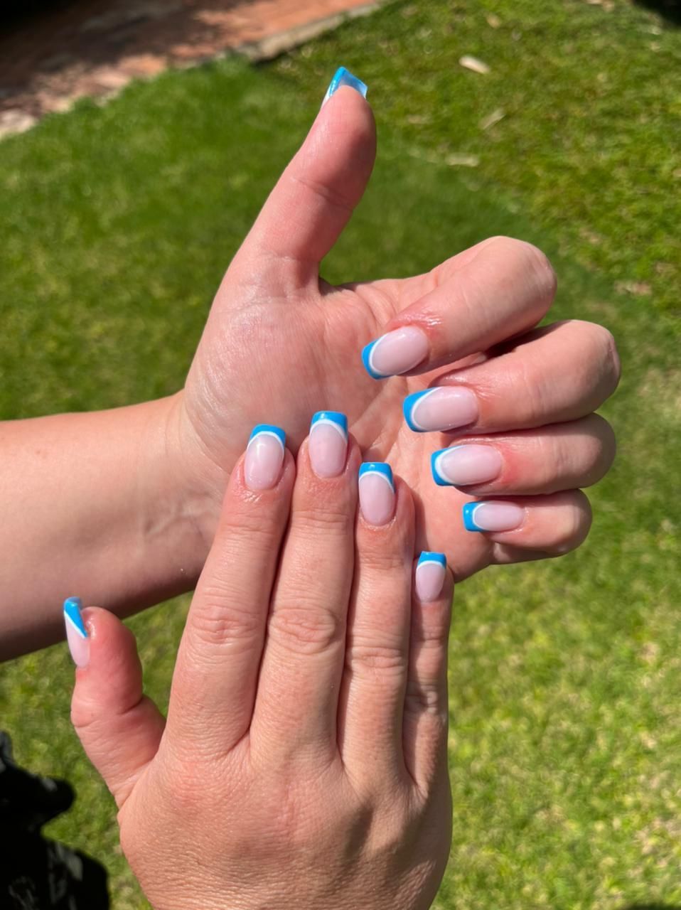 A close up of a person 's hands with blue french manicure.
