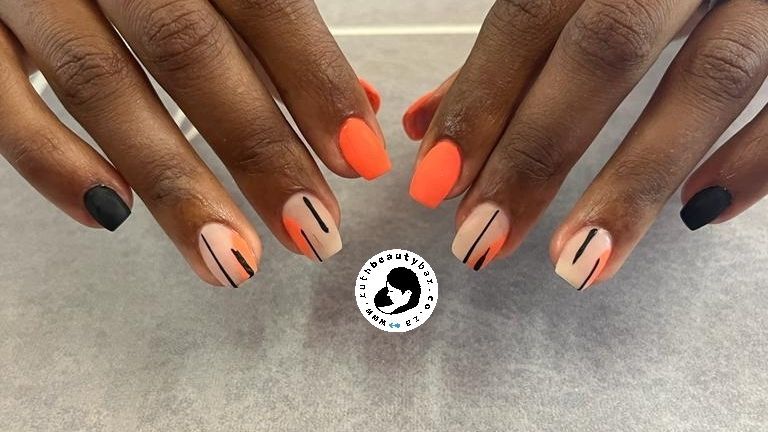 A close up of a woman 's nails with orange and black designs