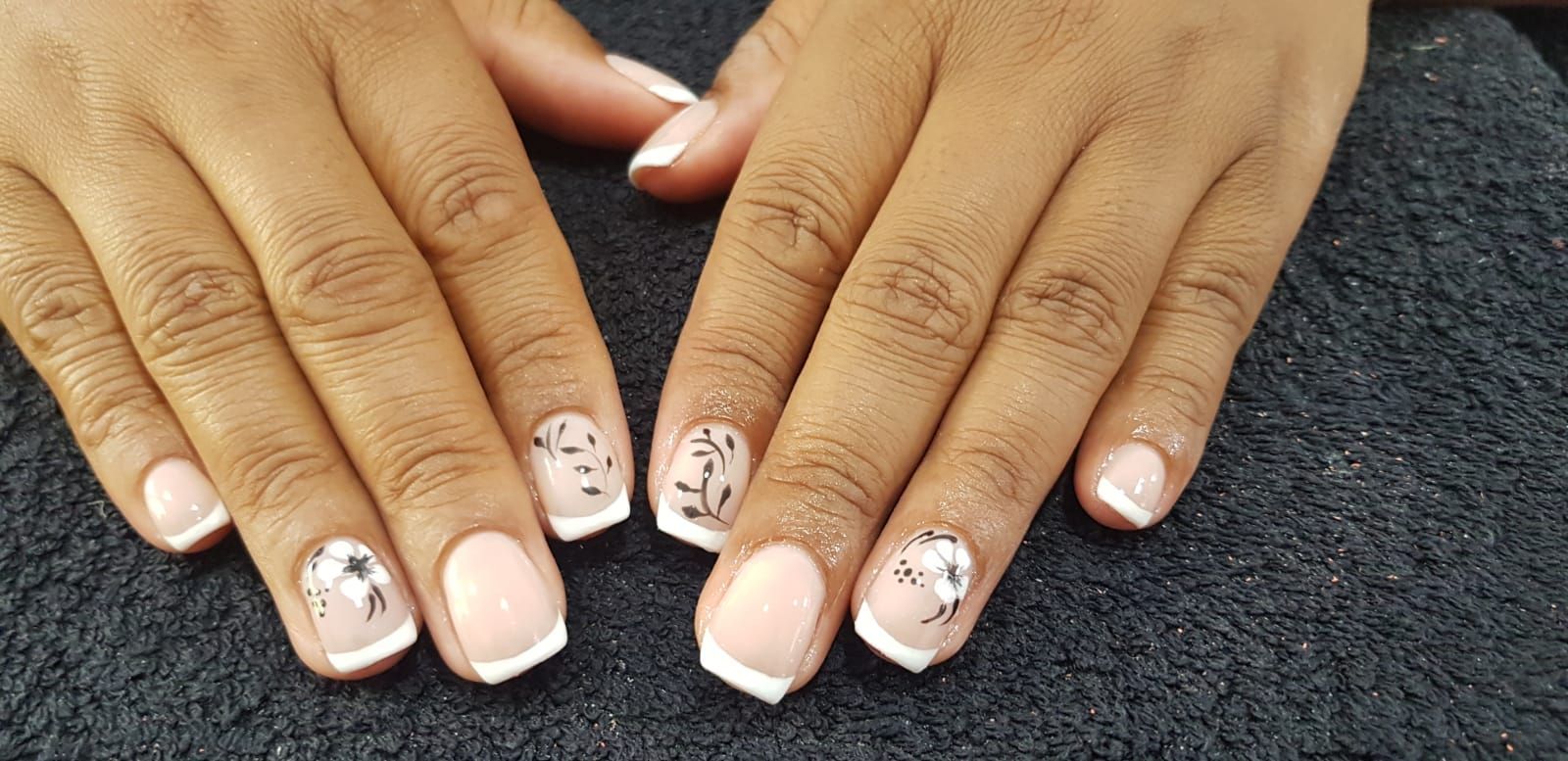 A close up of a woman 's nails with a french manicure.