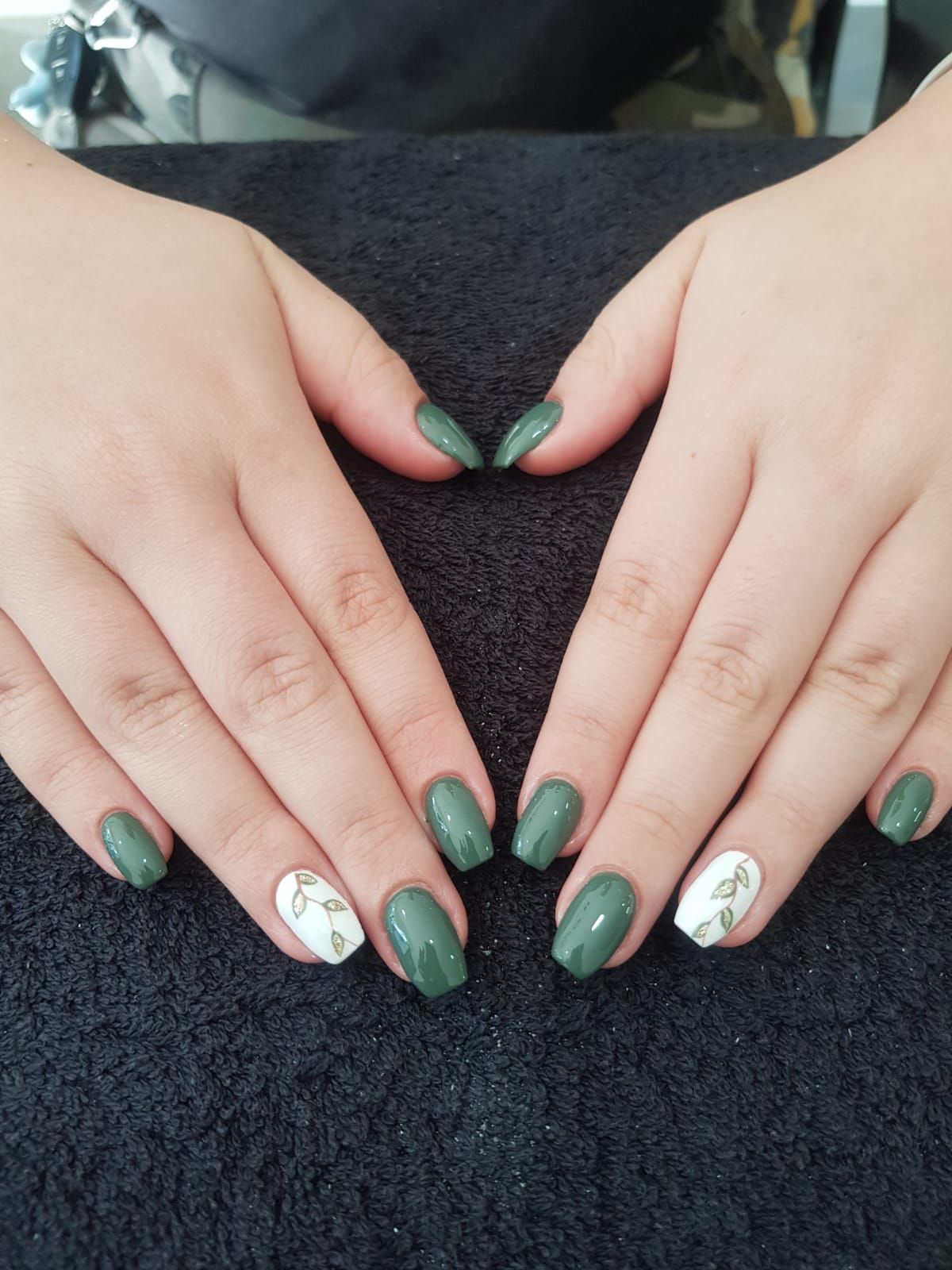 A woman 's hands with green and white nails make a heart shape