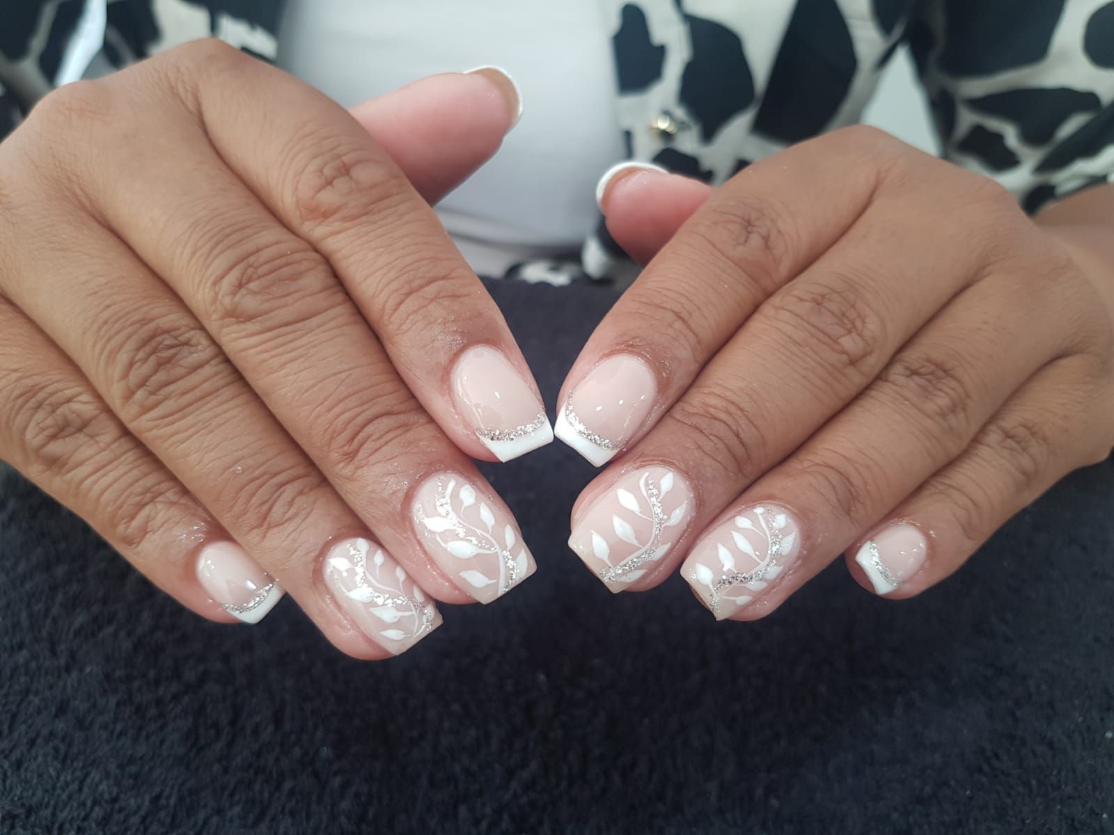 A close up of a woman 's hands with white nails