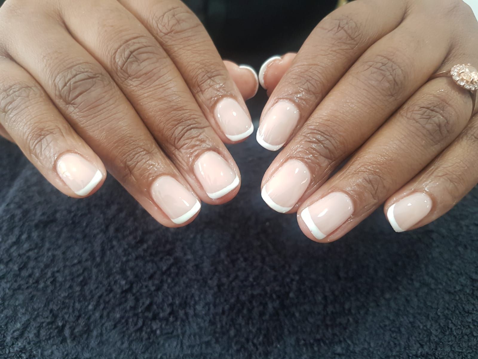 A close up of a woman 's nails with a french manicure.