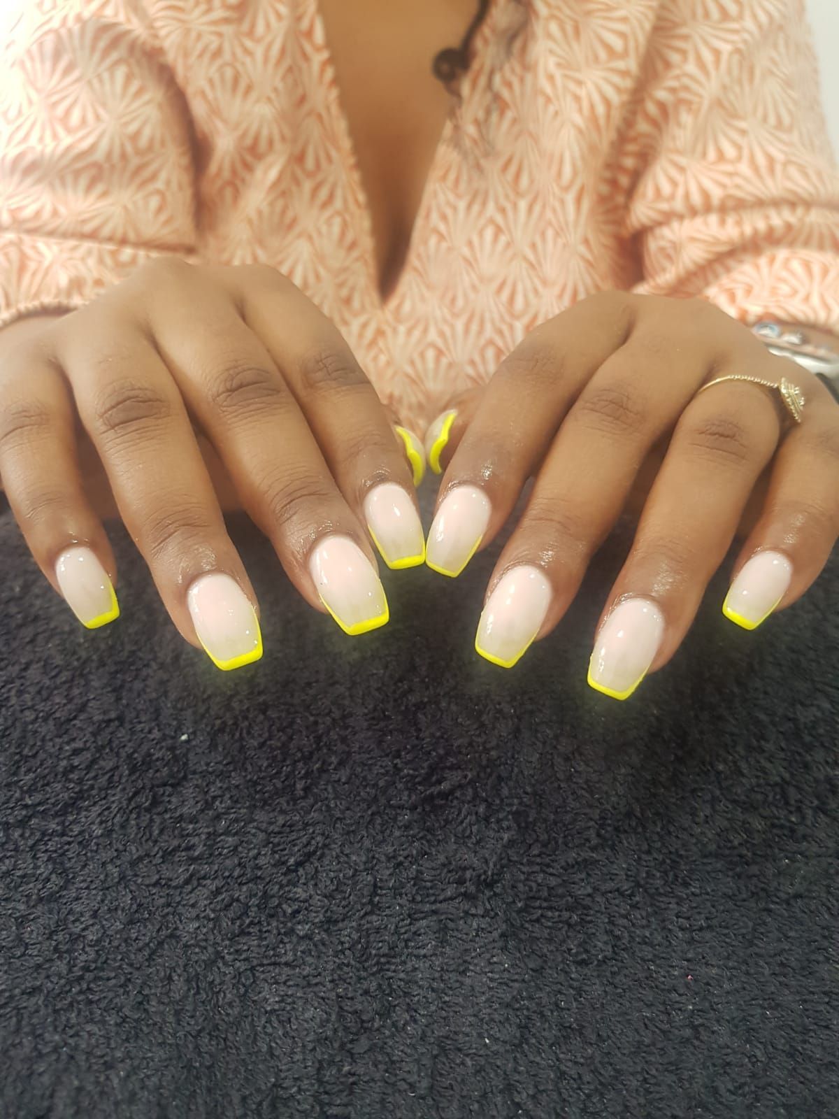 A close up of a woman 's nails with a yellow french manicure.