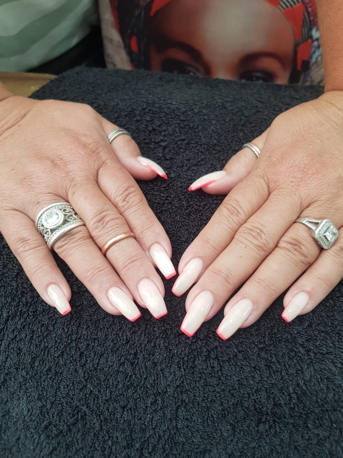 A woman 's hands with long nails and rings are making a heart shape.