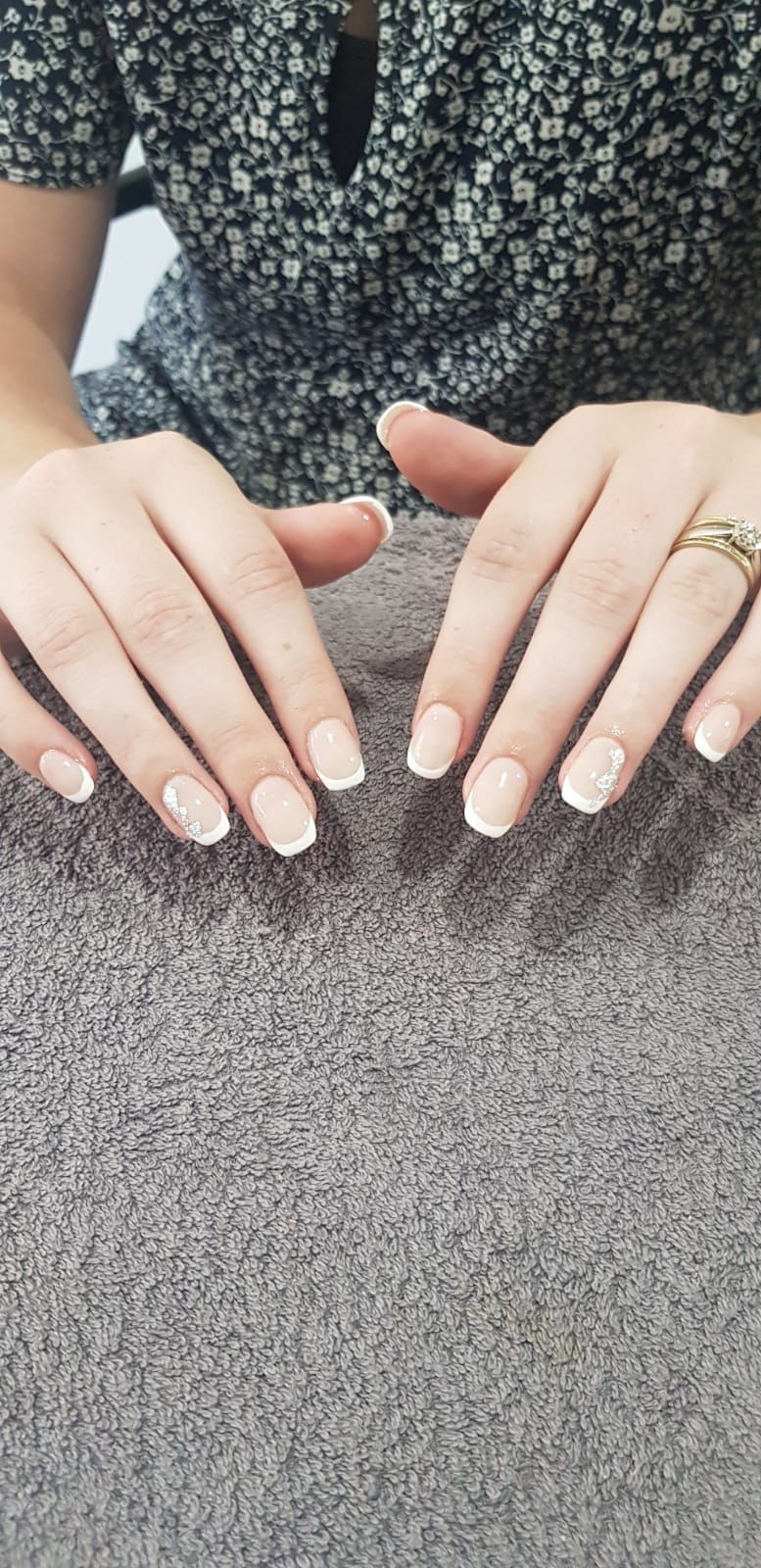 A close up of a woman 's hands with french manicure and a ring.