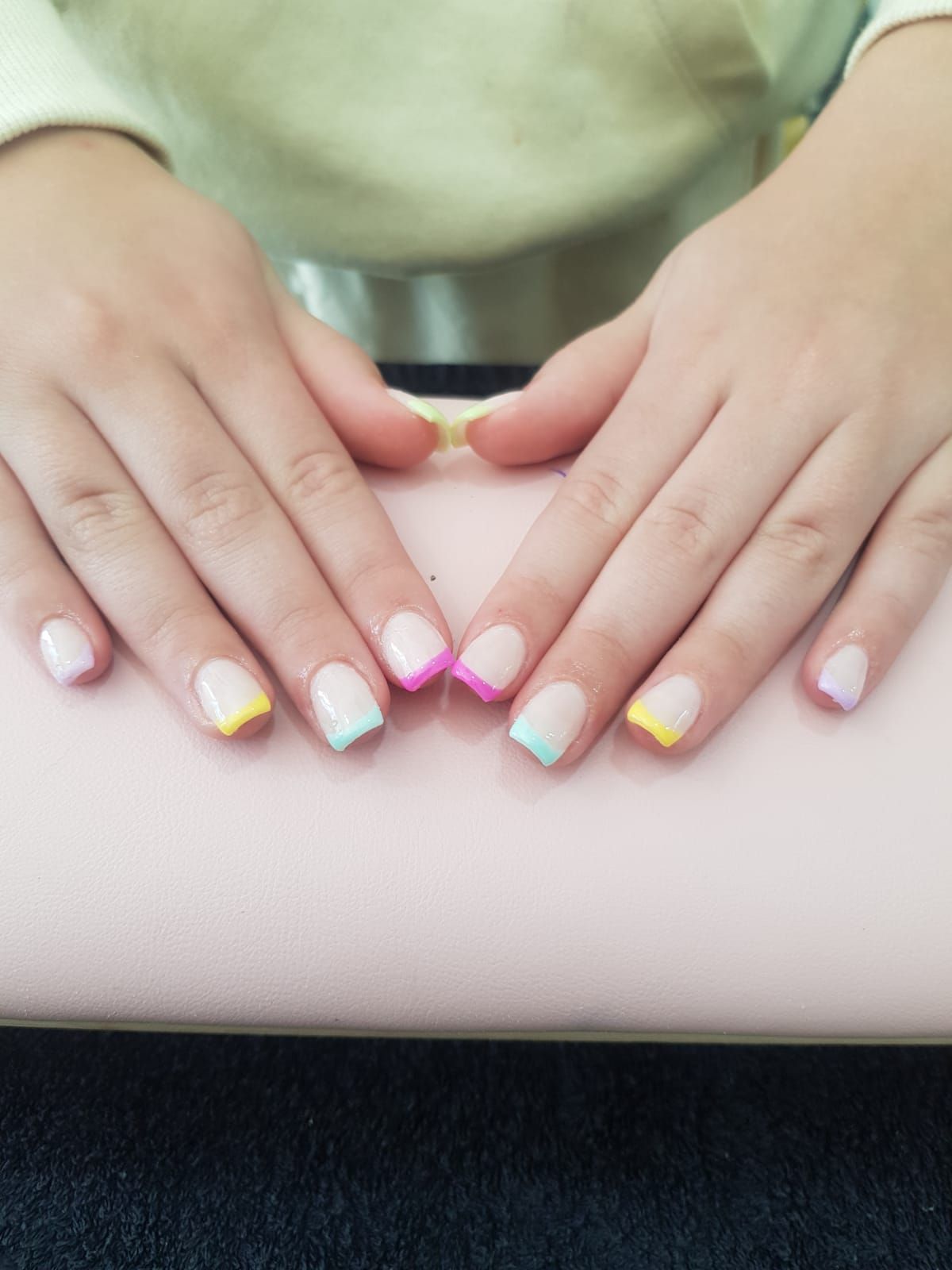 A close up of a person 's nails with colourful french tips