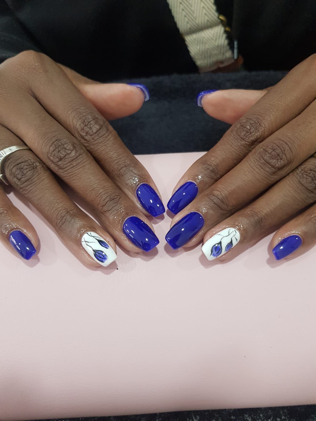 A close up of a woman 's hands with blue and white flower nail art