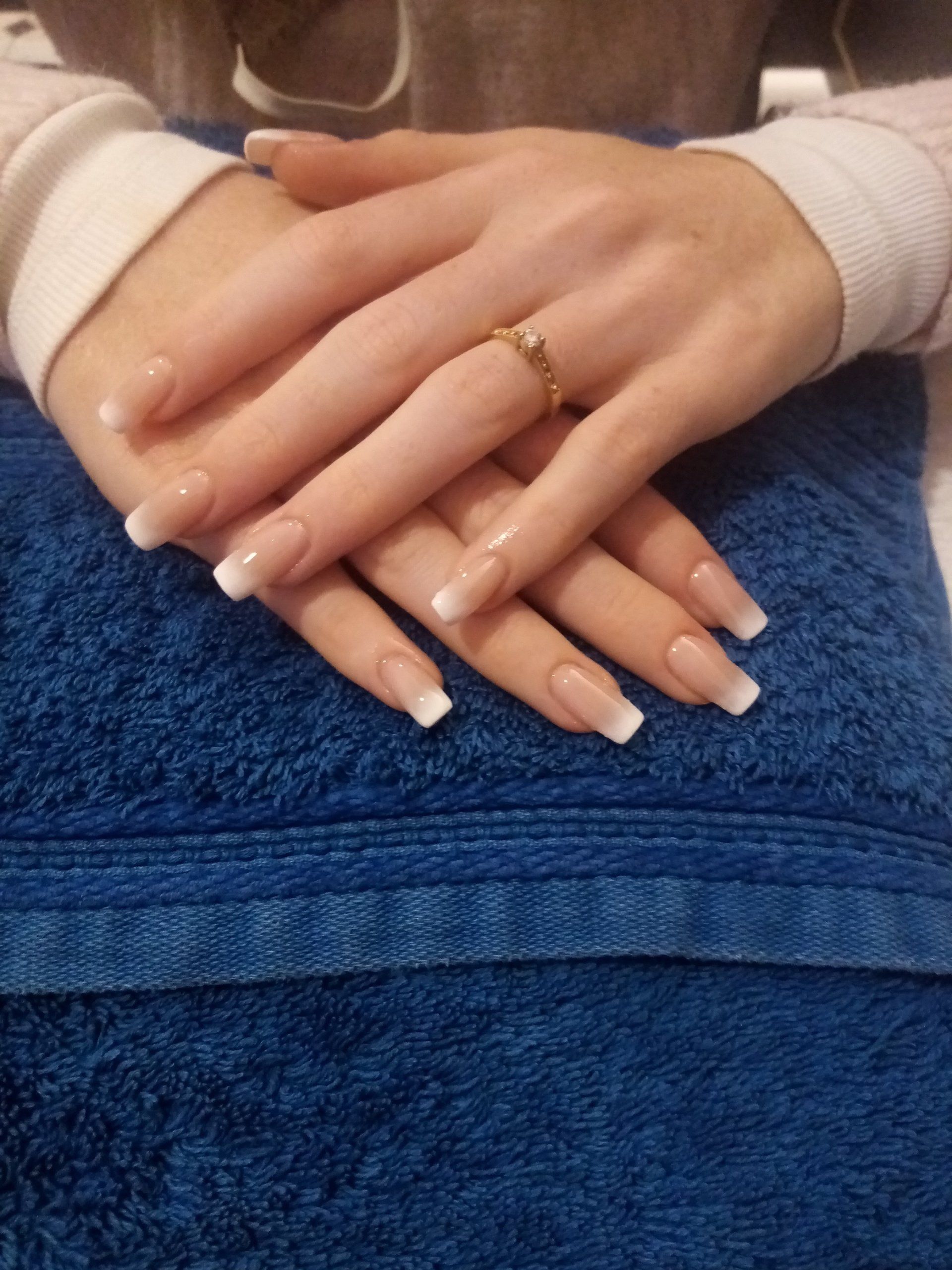 A woman with a ring on her finger is laying on a blue towel