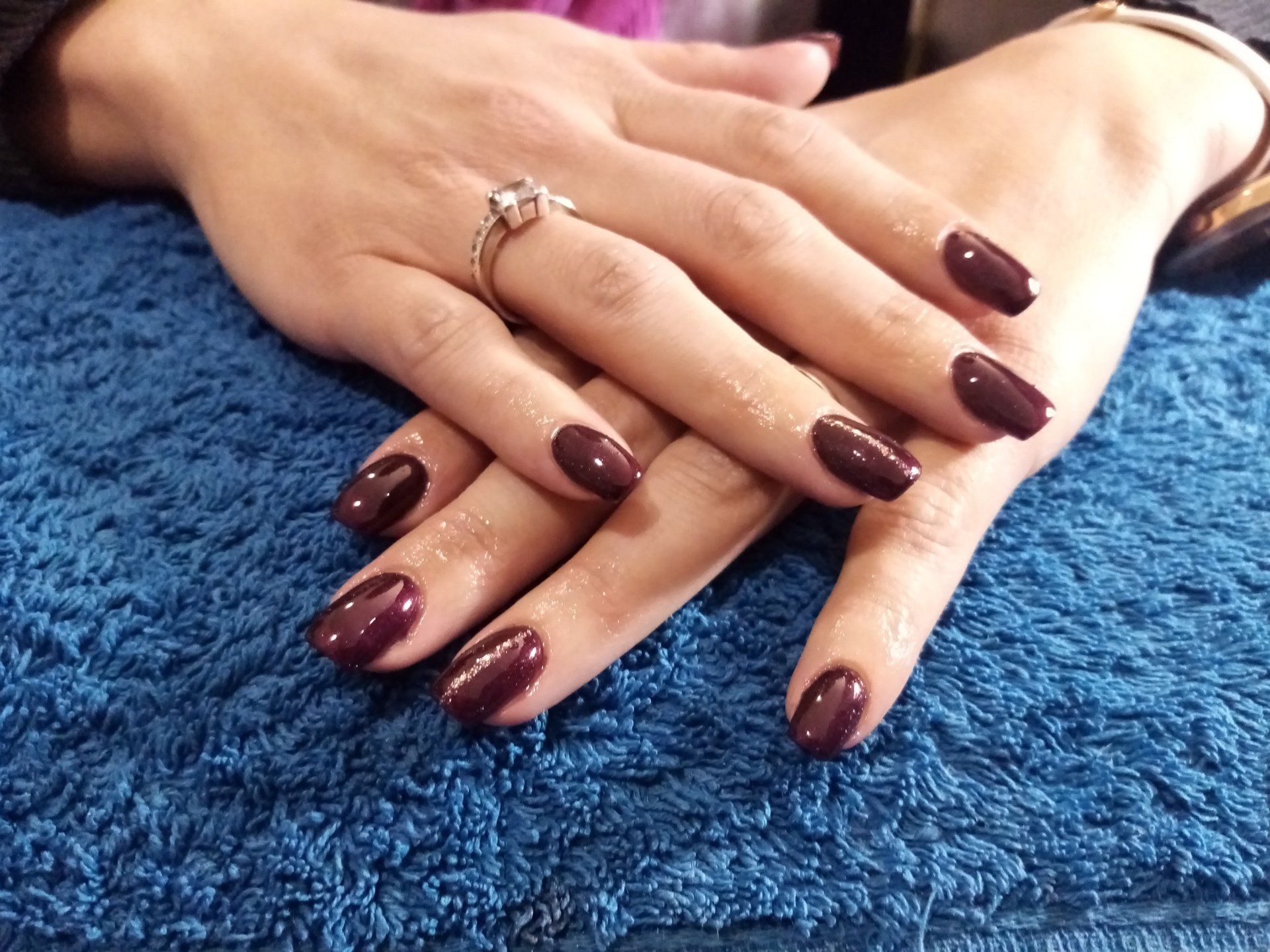 A woman 's hands with purple nails and a ring on her finger