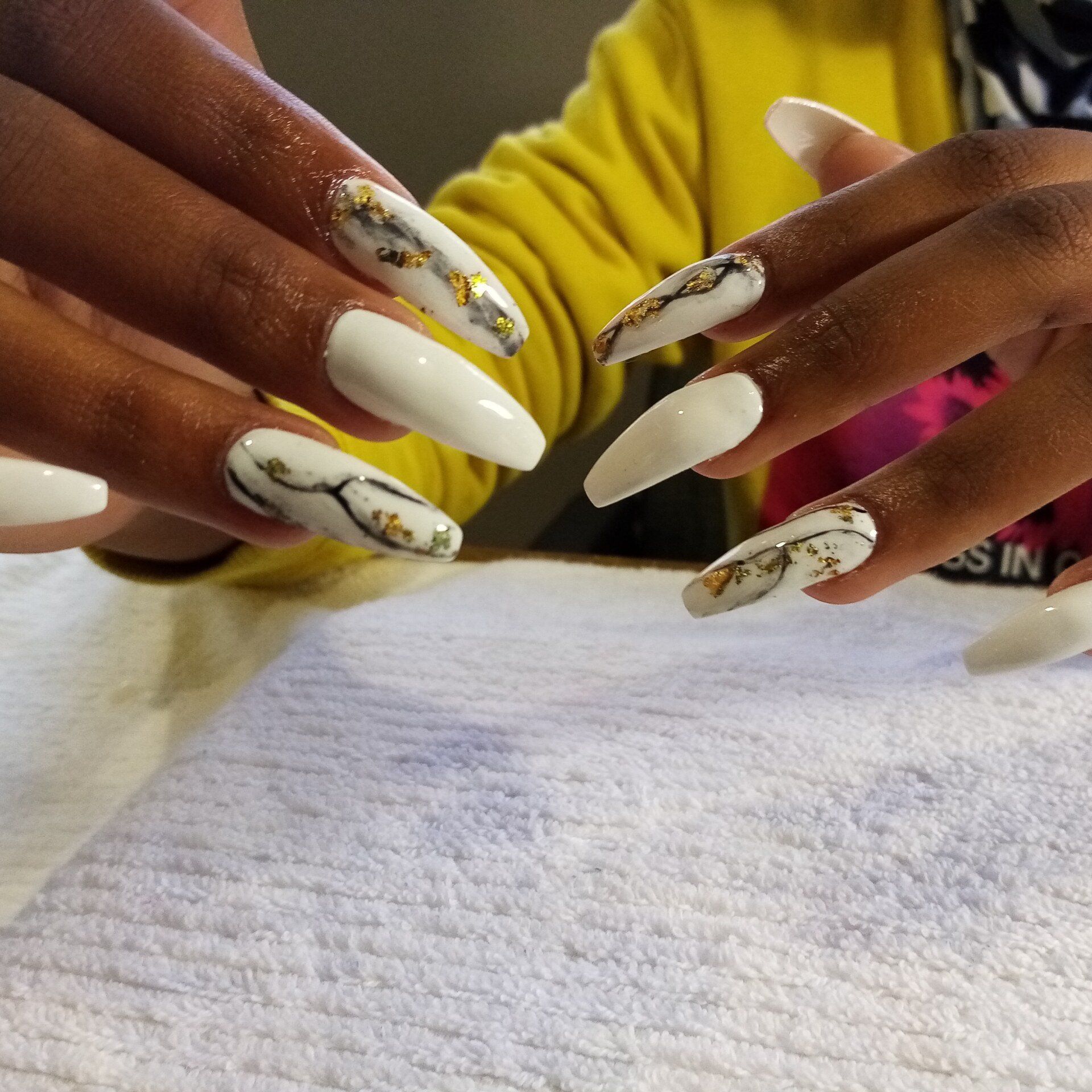 A woman 's nails are painted white and gold