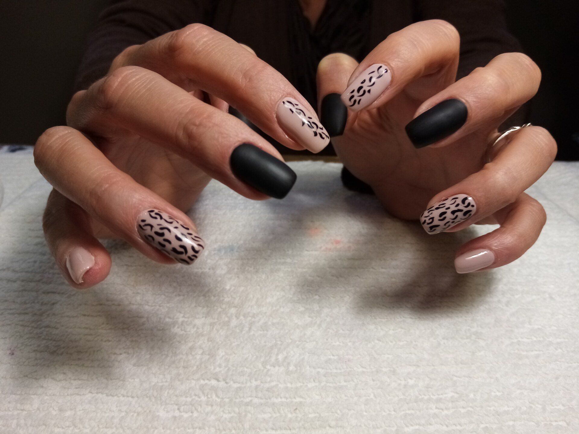 A close up of a woman 's hands with leopard print nails.