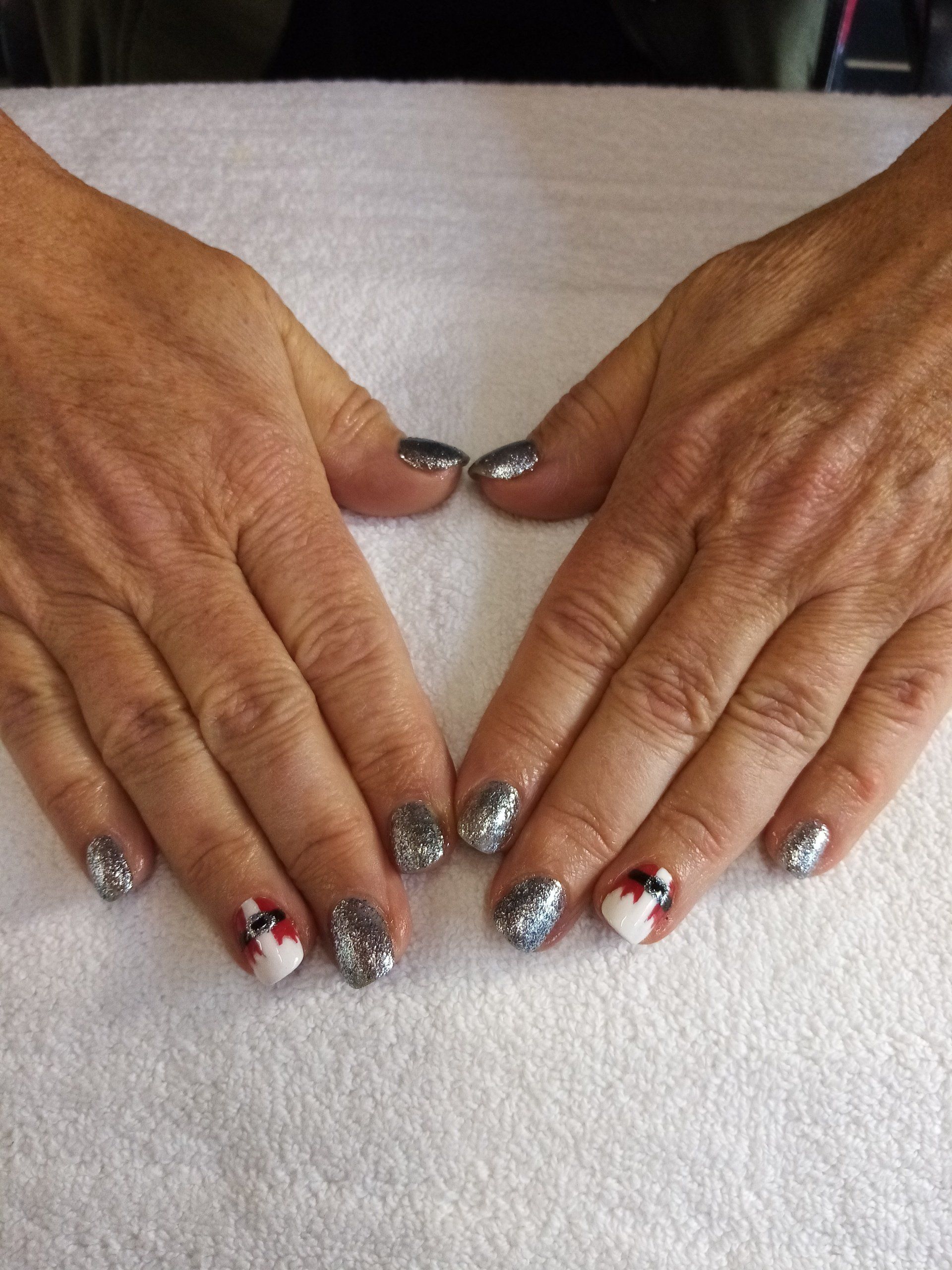 A close up of a person 's hands with silver nails on a white towel.