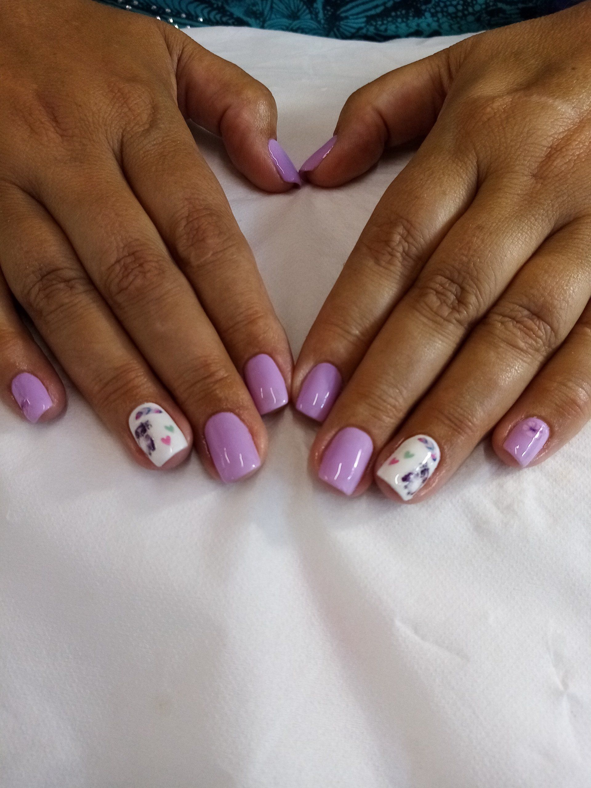 A close up of a woman 's hands with purple and white nails