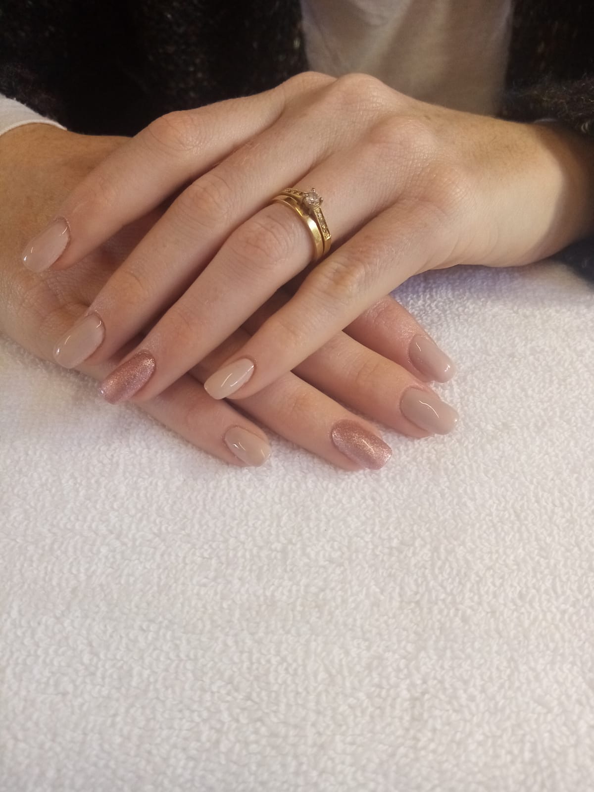 A woman 's hand with a gold ring on her finger