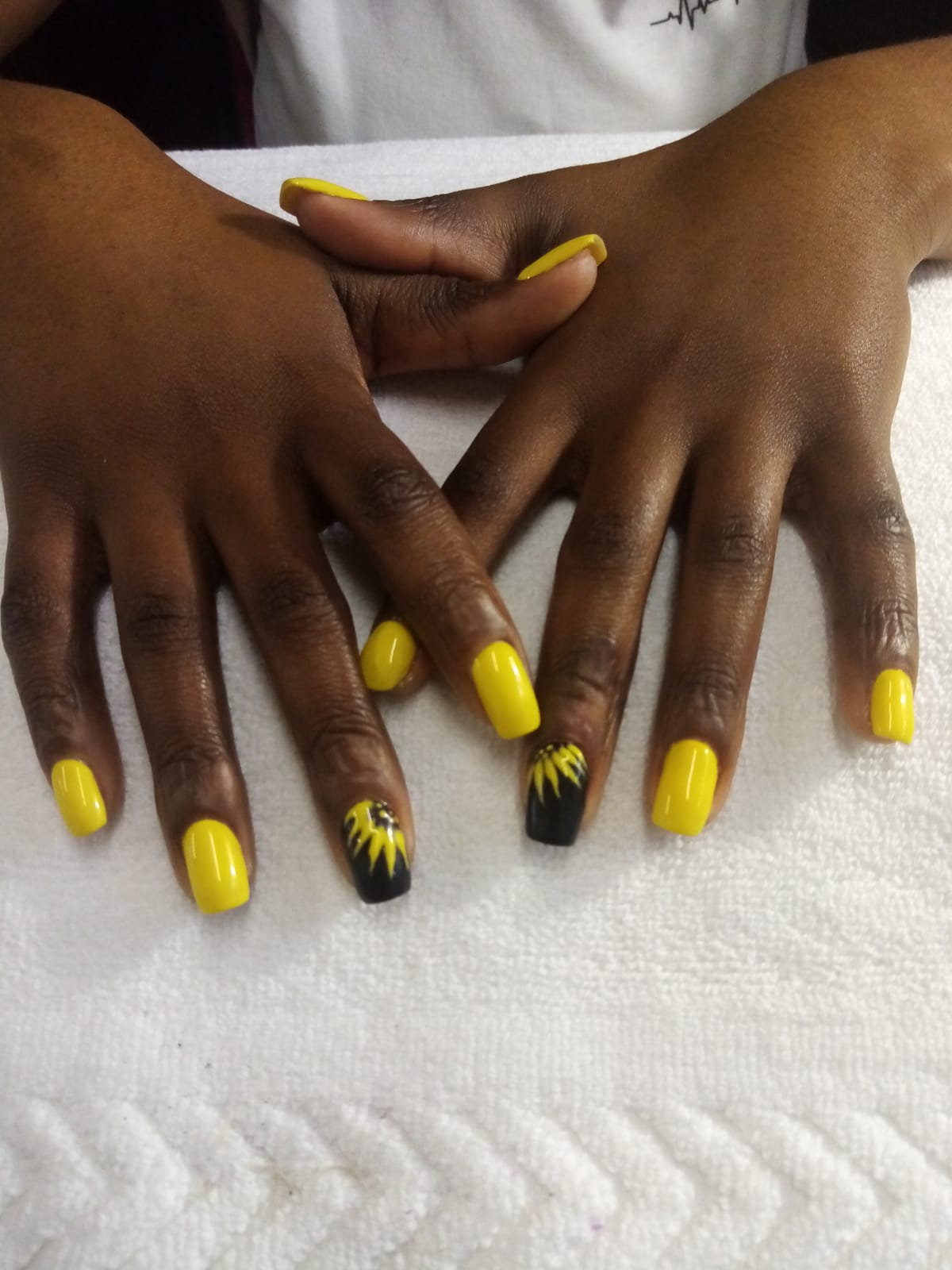 A close up of a person 's hands with yellow nails