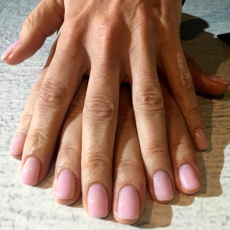 A close up of a woman 's hands with pink nails