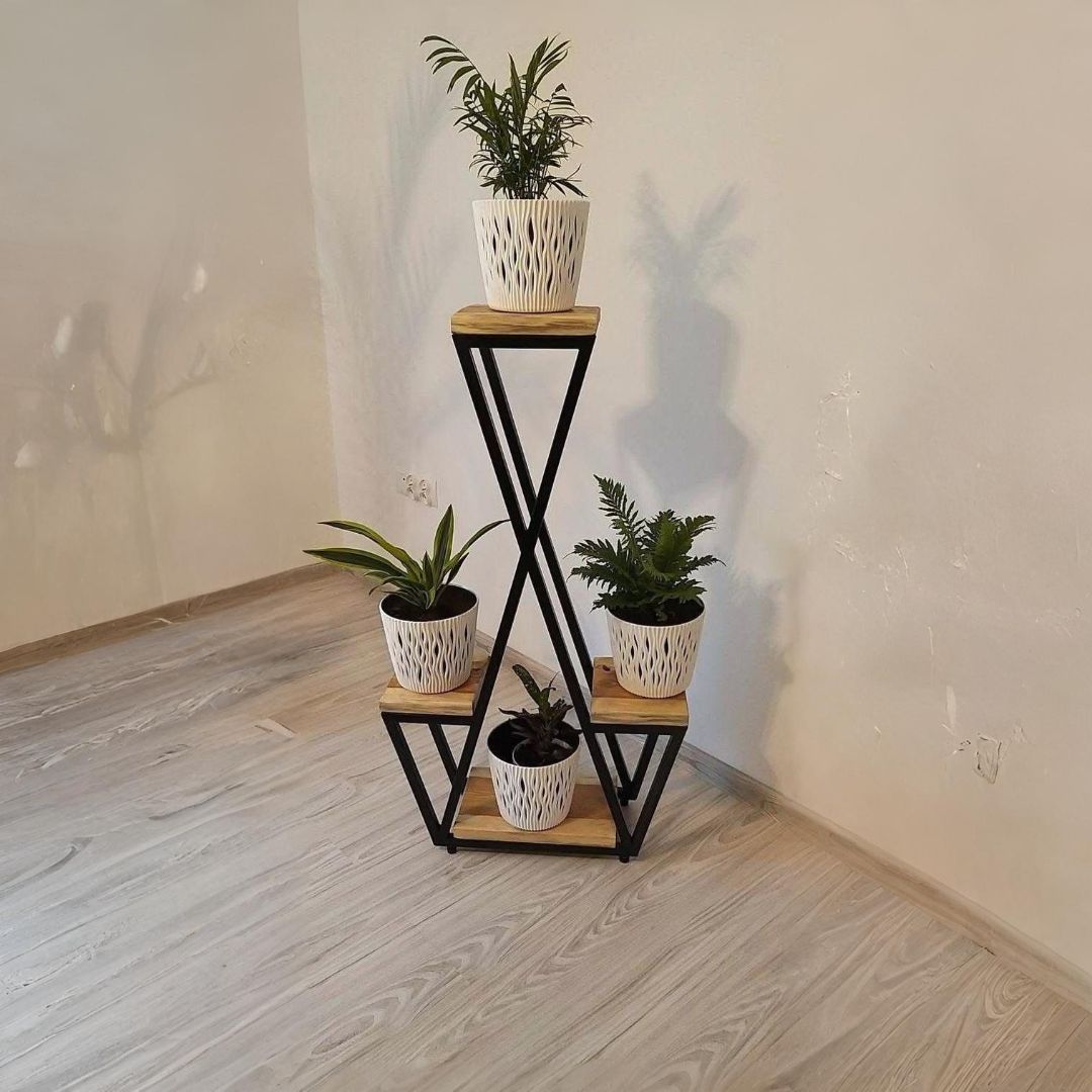 Soporte para plantas con estructura de metal negro y estantes de madera que sostienen tres plantas en macetas.