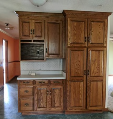 Oak kitchen cabinets with a microwave, countertop, and pantry.
