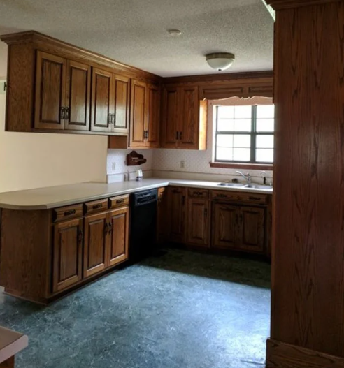 Oak kitchen with wooden cabinets, white countertops, and black appliances.