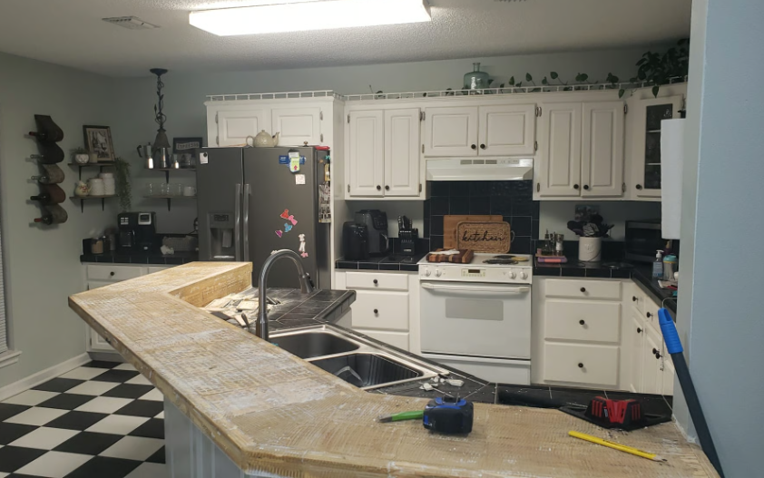 Kitchen with white cabinets, black countertops, and a black and white checkered floor.