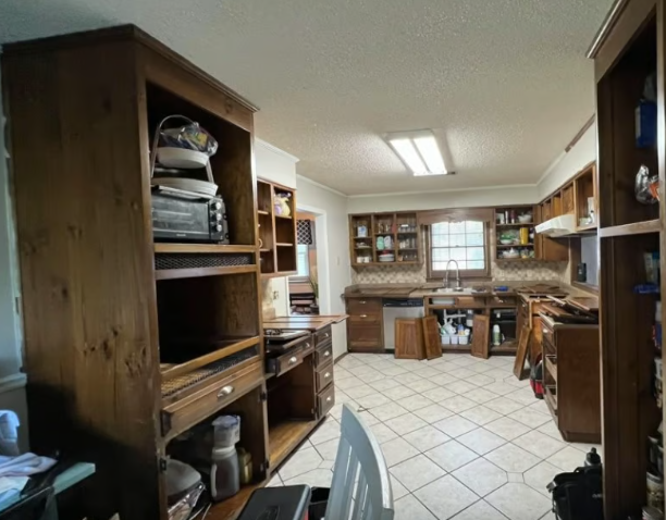 Kitchen with wooden cabinets, appliances, tile floor, and a window.