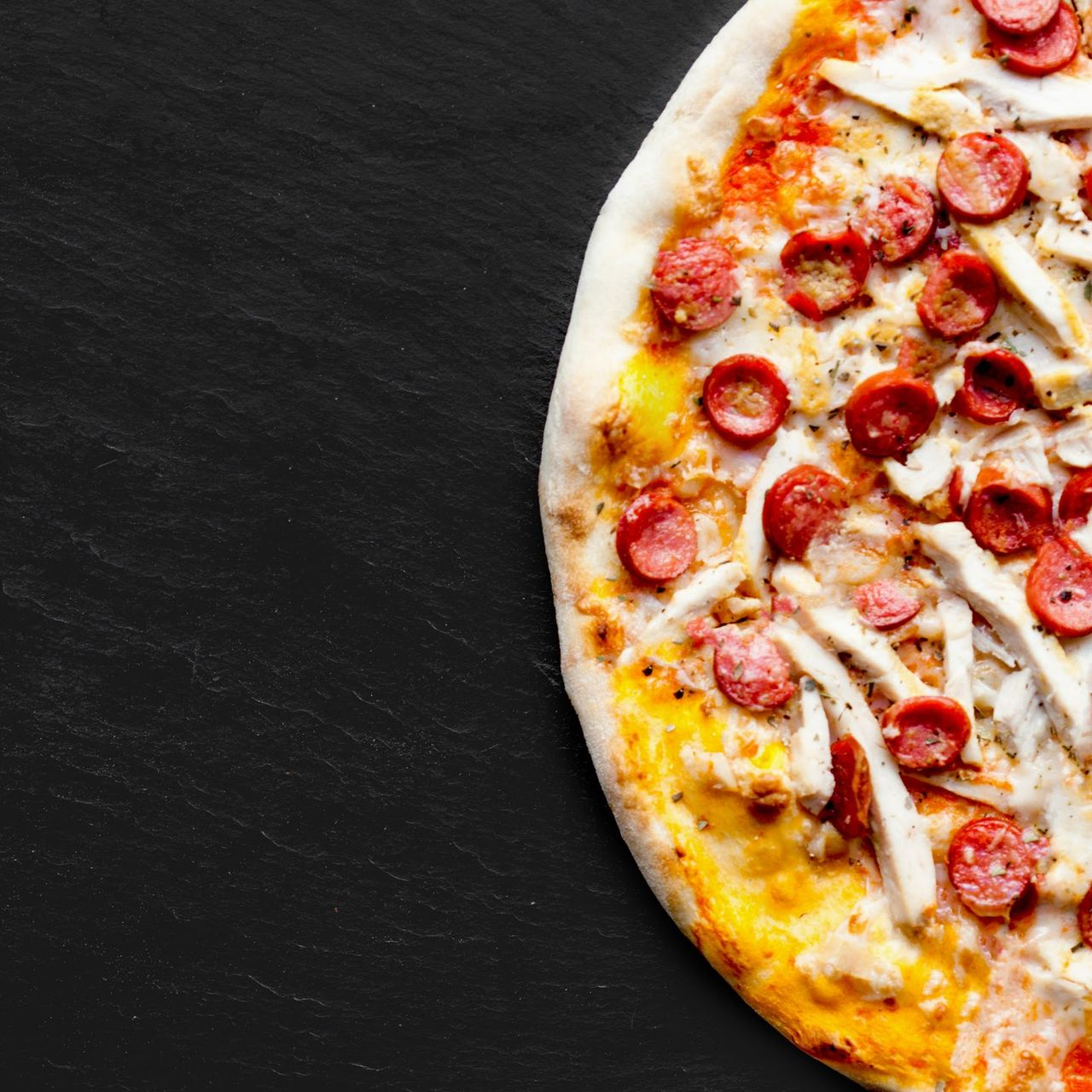 Una pizza è appoggiata su un bancone di marmo.