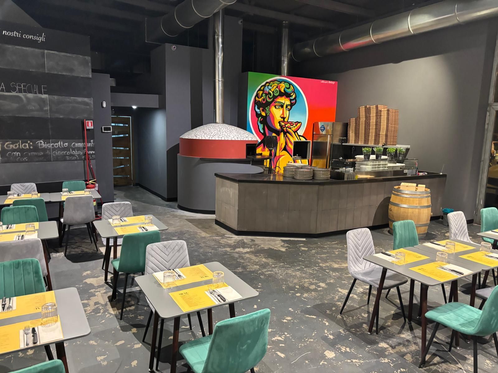 Un ristorante con tavoli e sedie e un dipinto di una donna sul muro.