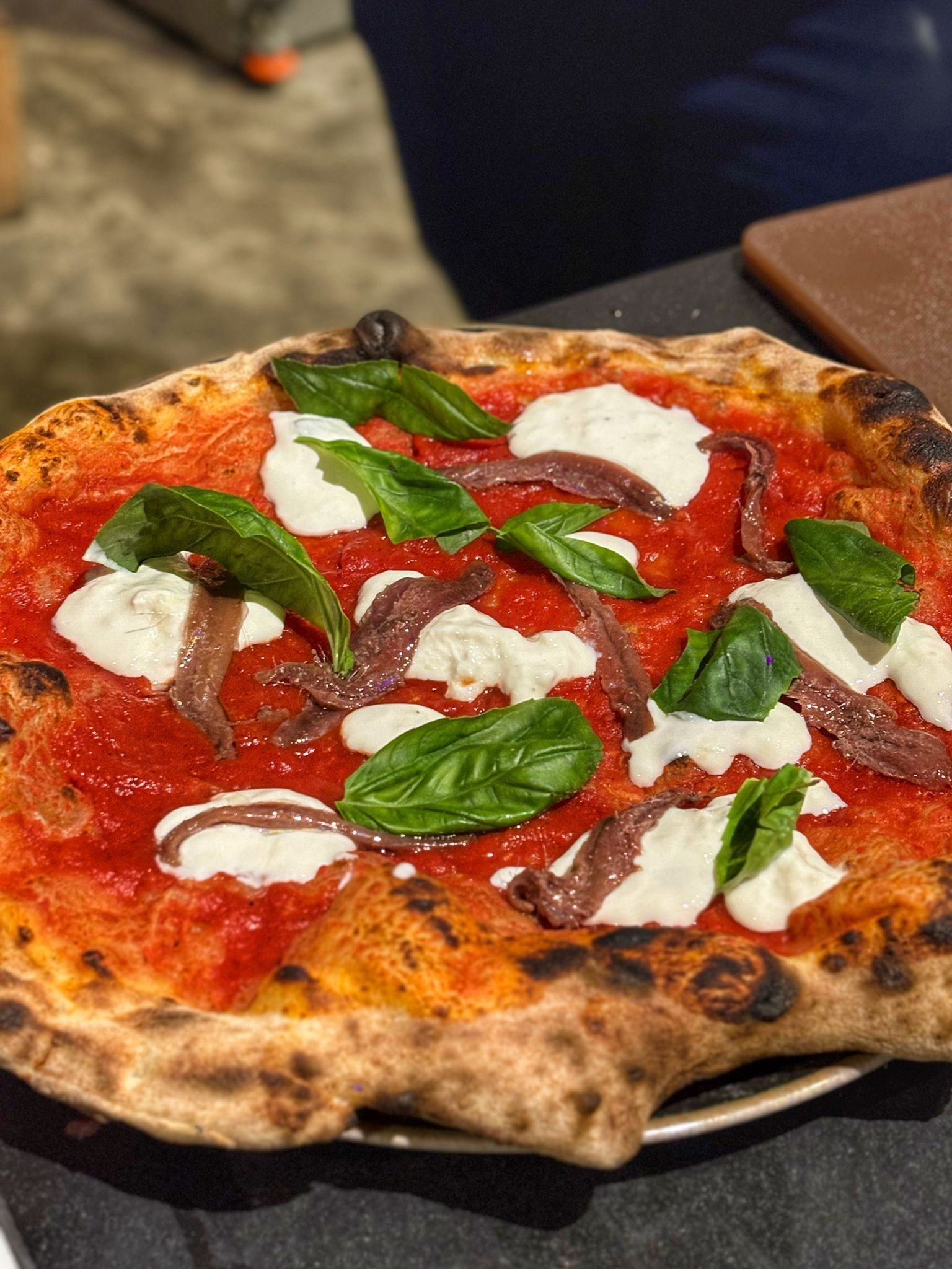 Una persona sta spalmando la salsa di pomodoro sull'impasto della pizza.