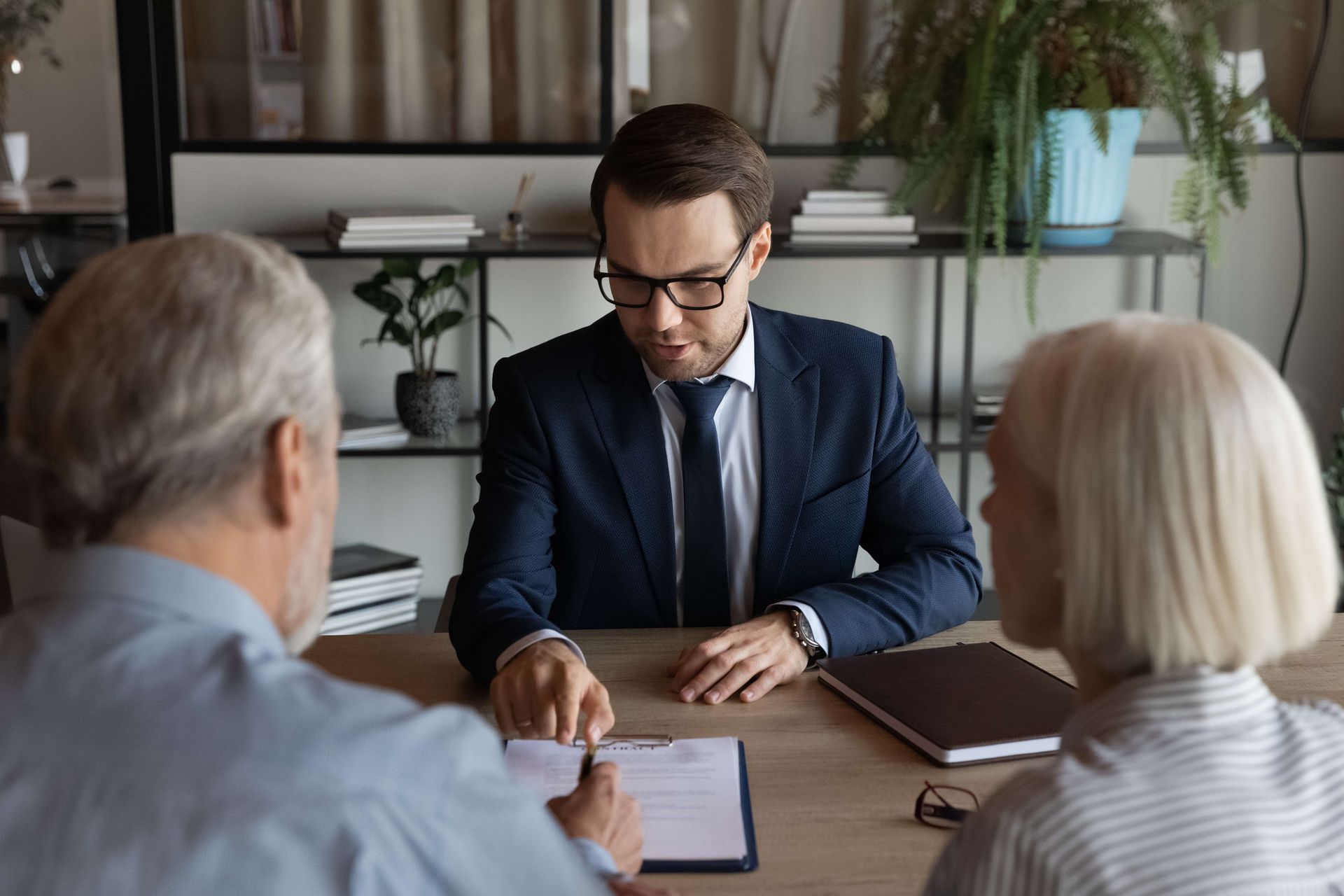 a man in a suit and tie is sitting at a table with two older people