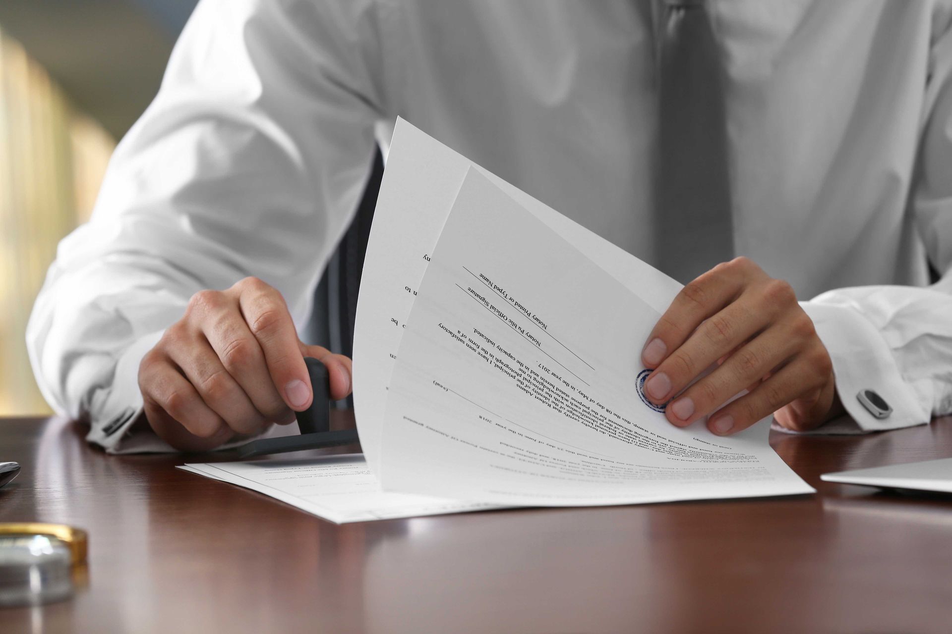 a man is sitting at a desk stamping a piece of paper