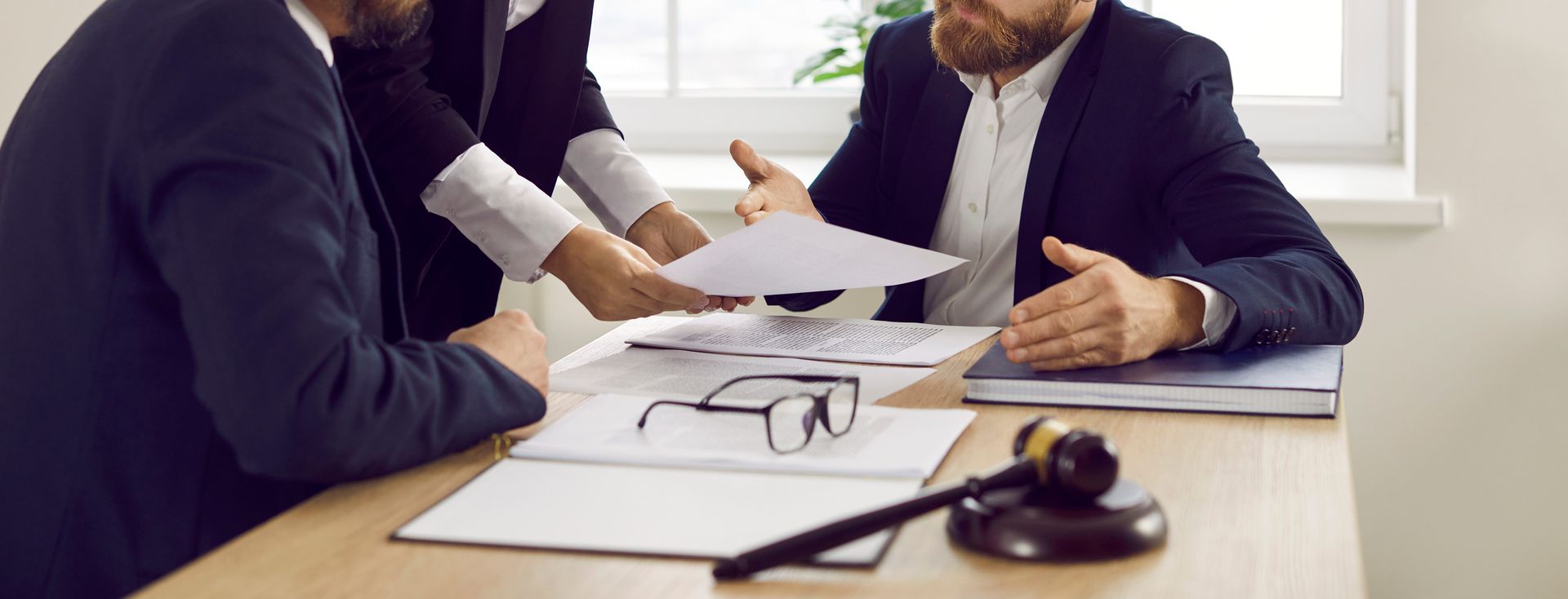 a group of men are sitting at a table with papers and a judge 's gavel
