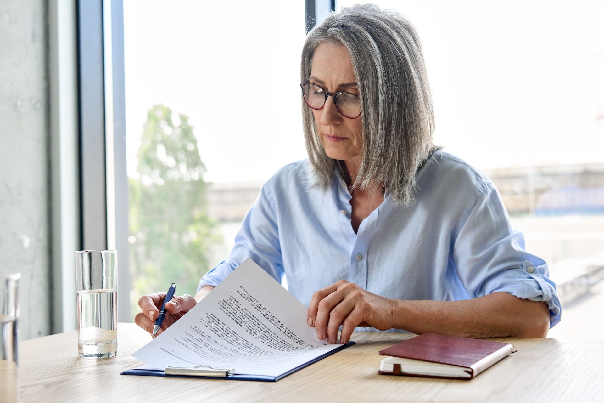 an older woman is sitting at a table reading a piece of paper