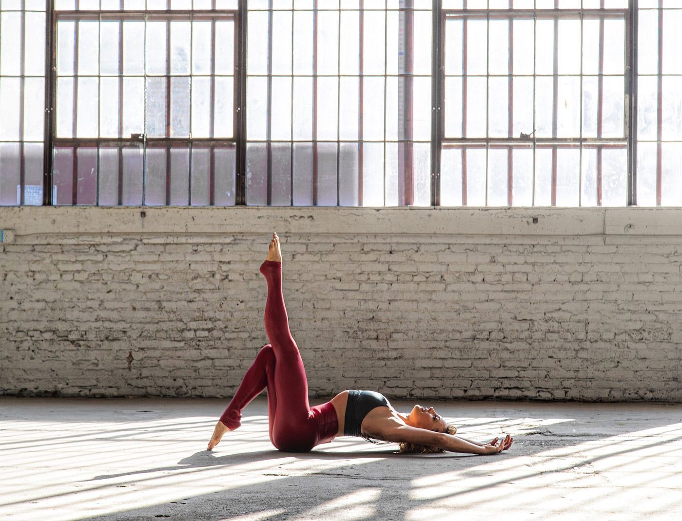 A woman is laying on the floor doing a yoga pose.