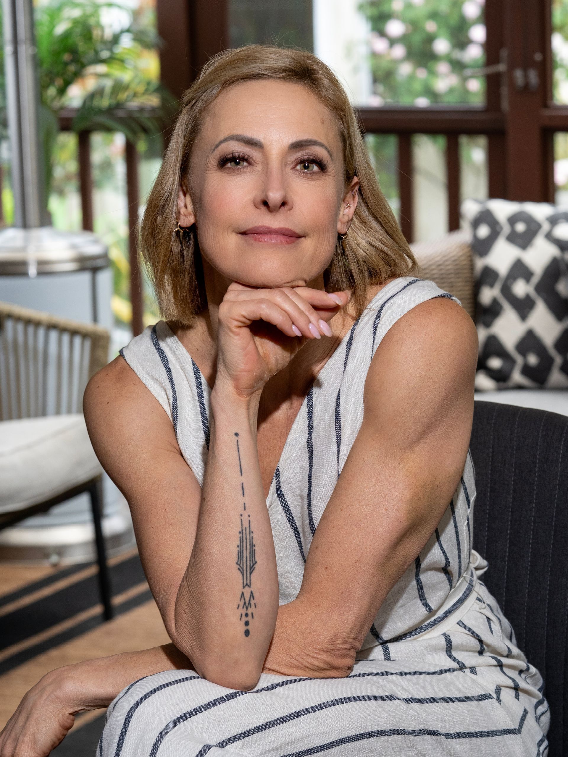 A woman with a tattoo on her arm is sitting in a chair.