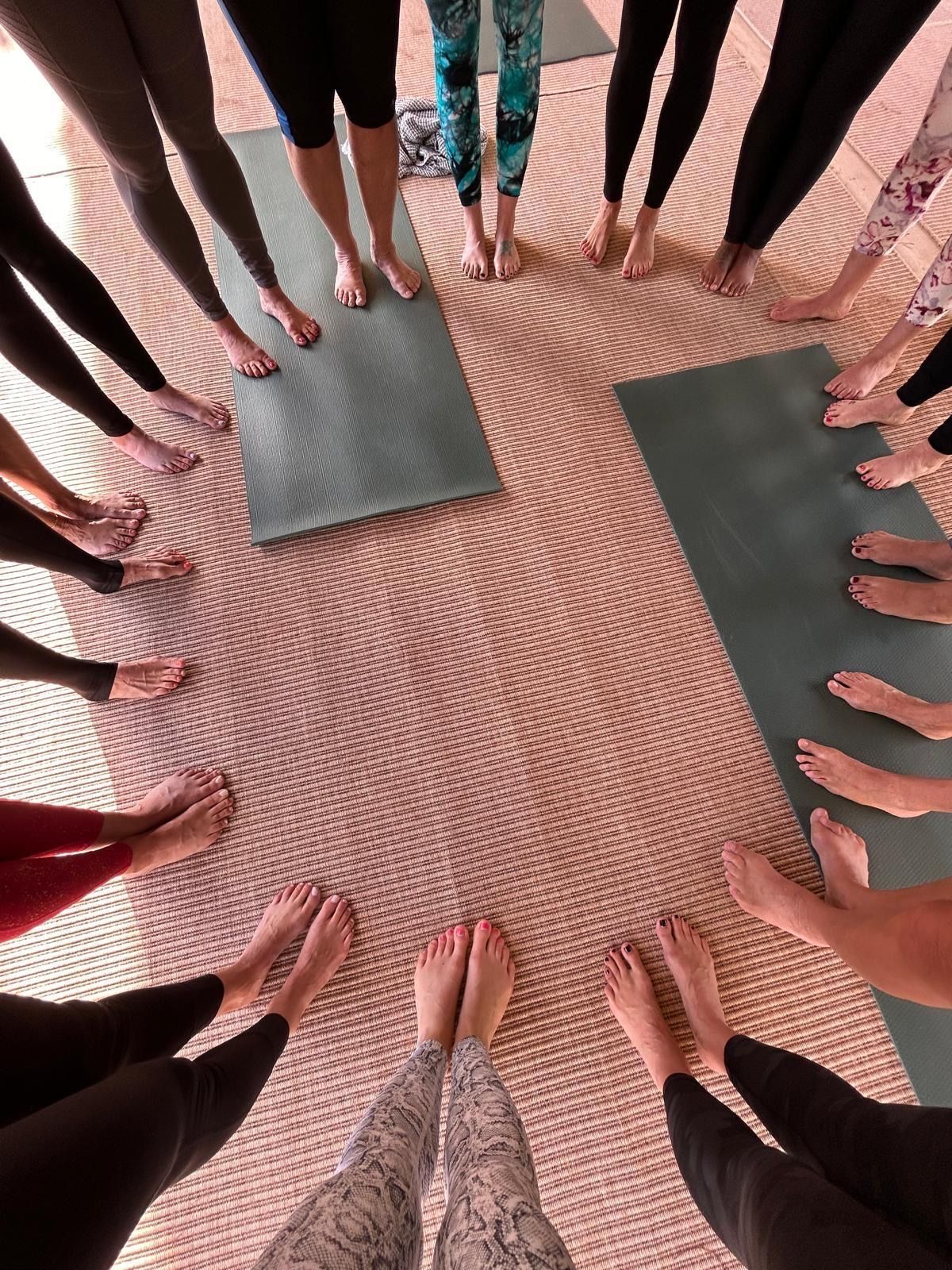 A group of people are standing in a circle with their feet on yoga mats.