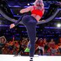 A woman in a red top and black leggings is kicking