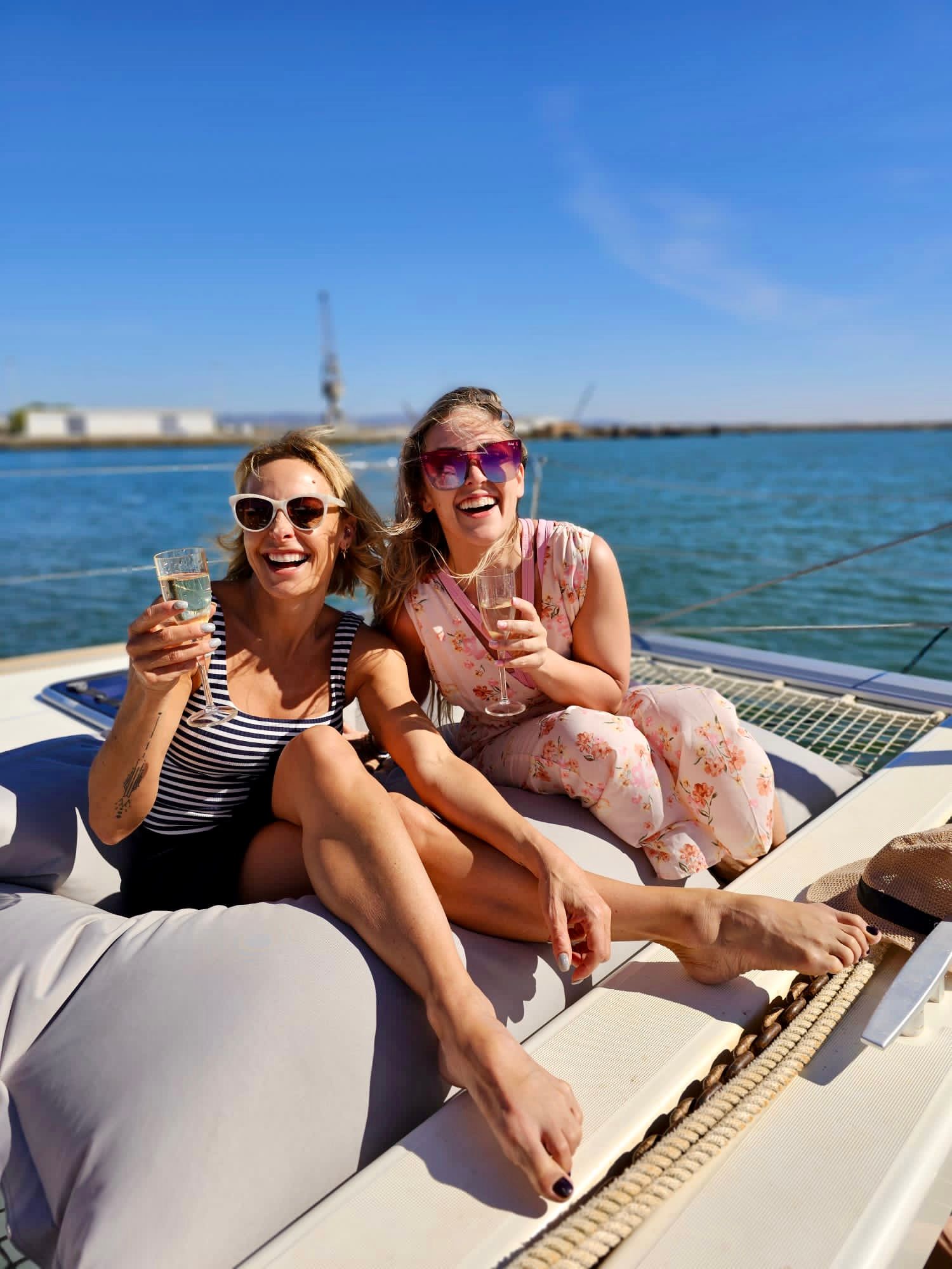 Two women are sitting on a boat holding glasses of champagne.