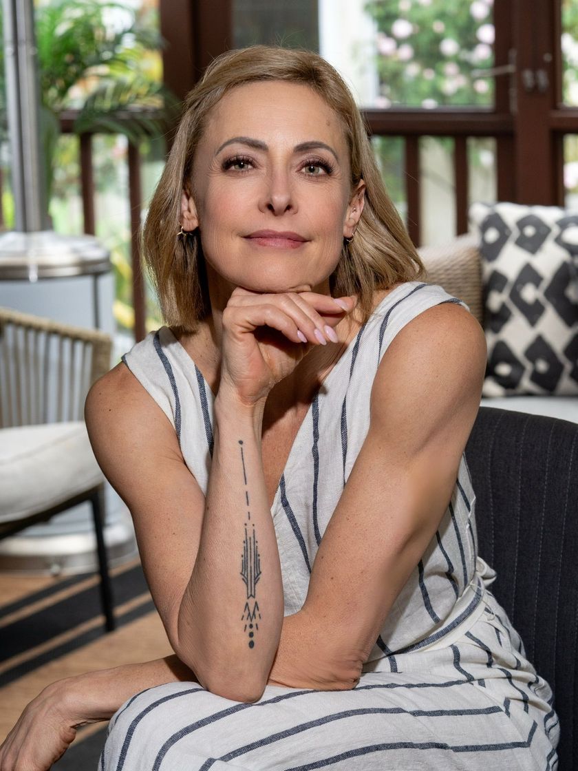 A woman in a striped dress is sitting on a couch with her hand on her chin.