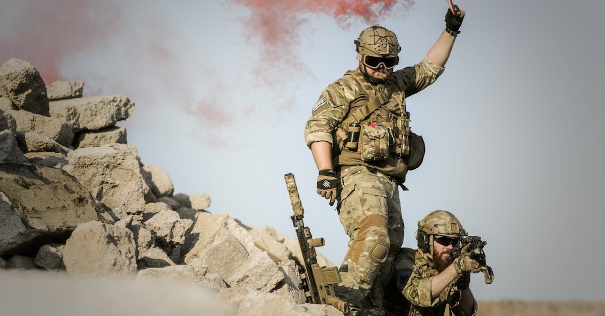 Two soldiers are standing on top of a pile of rocks.