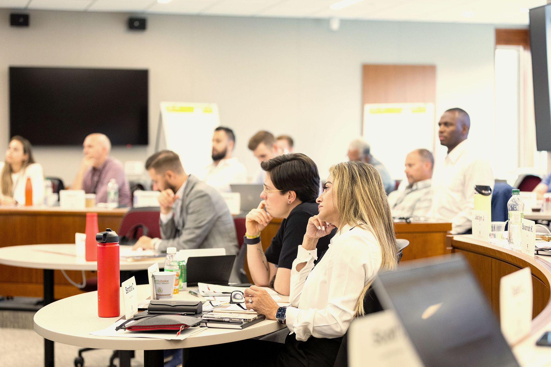 A group of people are sitting at tables in a conference room.
