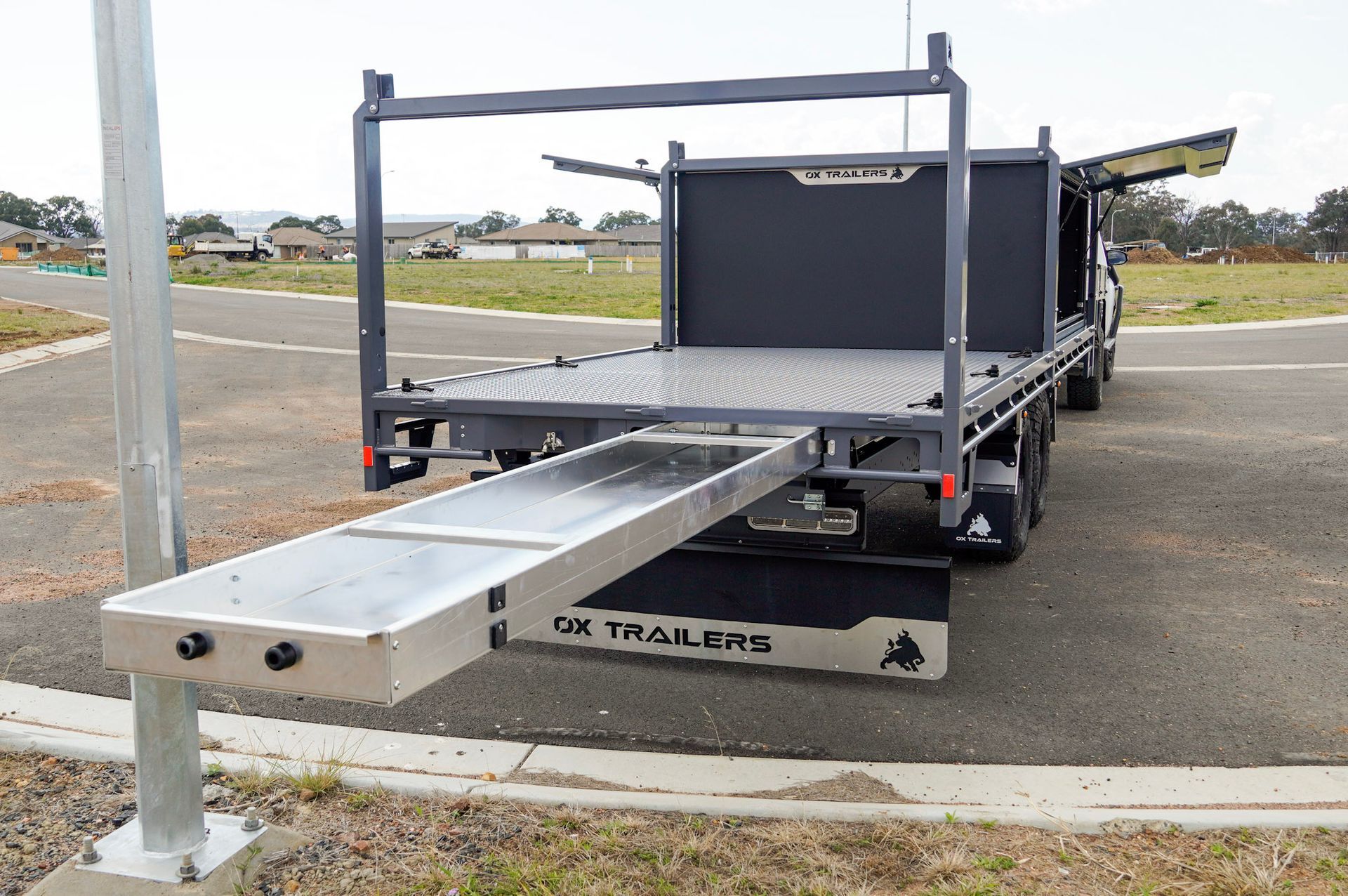 6m long flat top trailer built custom by ox trailers with ladder racks, lift-off canopy and rear drawer at rural queenslad construction site.