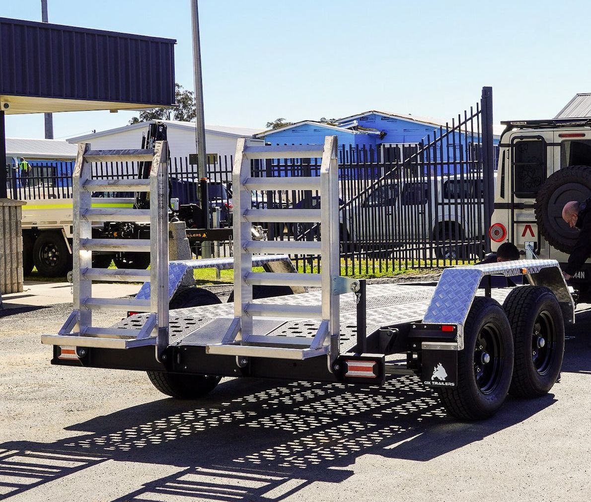 heavy duty drop-down ramps for ox trailers plant trailer, towed behind 4x4 for excavator transport at industrial yard.