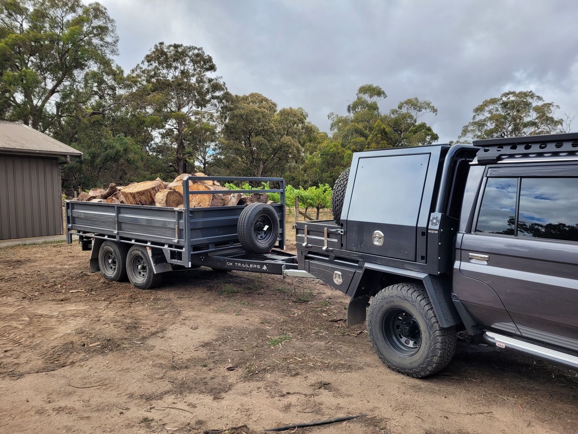 4.2m by 2.1m Tipper Trailer loaded with firewood and towed behind an 80 series Land Cruiser.