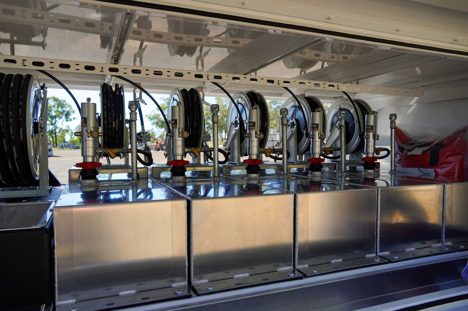 heavy duty custom flat top trailer for gee building at rural construction site with toolbox and canopy doors open.