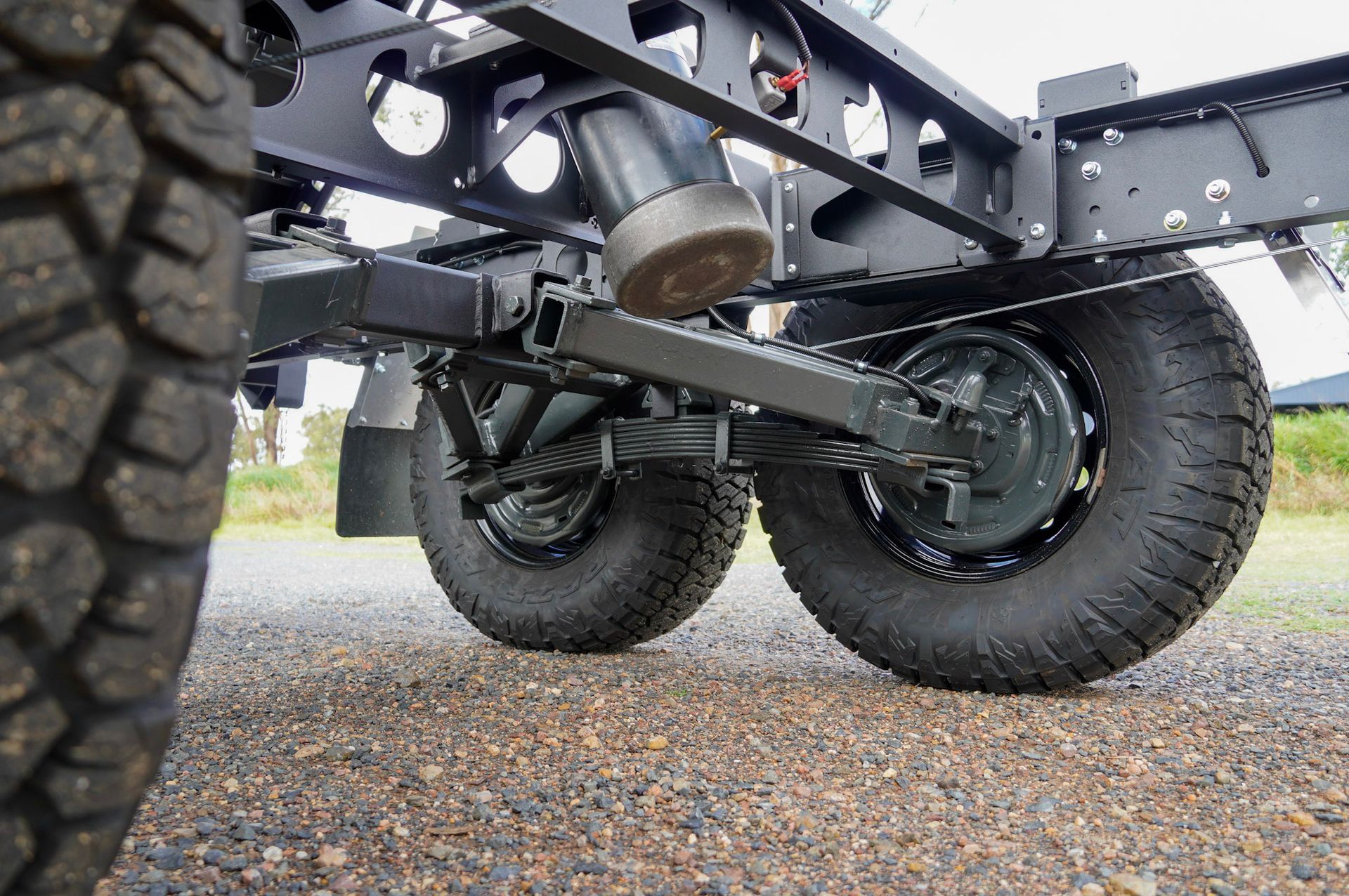 heavy duty custom flat top trailer for gee building at rural construction site with toolbox and canopy doors open.
